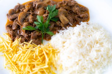 Geleneksel fileminyon mantarlı stroganoff, patates kızartması ve pilav.