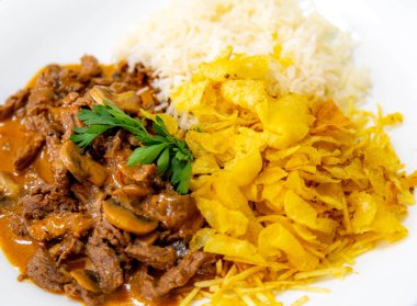 Geleneksel fileminyon mantarlı stroganoff, patates kızartması ve pilav.