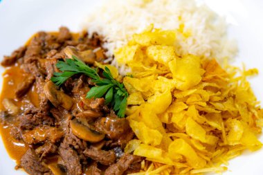 Geleneksel fileminyon mantarlı stroganoff, patates kızartması ve pilav.