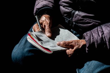 Yaşlı elleri ve dramatik aydınlatma ve yansıması olan kelime bulmacası