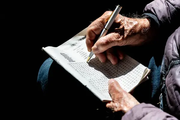 Yaşlı elleri ve dramatik aydınlatma ve yansıması olan kelime bulmacası