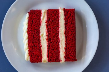 Geleneksel ve lezzetli kırmızı kadife pasta beyaz tabakta izole edilmiş.