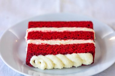 Geleneksel ve lezzetli kırmızı kadife pasta beyaz tabakta izole edilmiş.