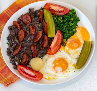 Kaba, besleyici Brezilya yemekleri, yumurtalı siyah fasulye güveci, ızgara sosis, turşu ve doğal fermantasyon, lahana ve sebze. Gerçek yemek.