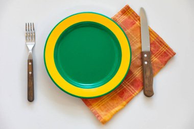 Renkli boş tabak beyaz arka planda izole edilmiş ve yanında da kırsal çatal bıçak takımı var.