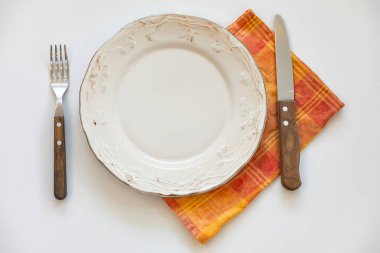 Renkli boş tabak beyaz arka planda izole edilmiş ve yanında da kırsal çatal bıçak takımı var.