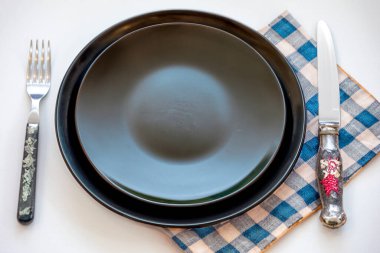 Renkli boş tabak beyaz arka planda izole edilmiş ve yanında da kırsal çatal bıçak takımı var.