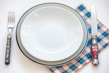 Renkli boş tabak beyaz arka planda izole edilmiş ve yanında da kırsal çatal bıçak takımı var.