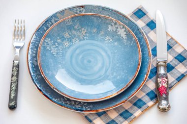 Renkli boş tabak beyaz arka planda izole edilmiş ve yanında da kırsal çatal bıçak takımı var.