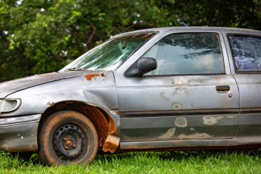 Eski, hava hasarlı, paslı terk edilmiş bir araba.