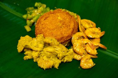 Hakiki Brezilya acaraj mantı, vatap, caruru, kurutulmuş karides, salata ve palmiye yağında kızartılmış. Muz yaprağında servis edilir.