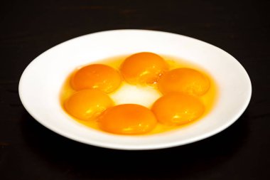 Beyaz tabakta yumurta sarısı siyah arka planda izole edilmiş.
