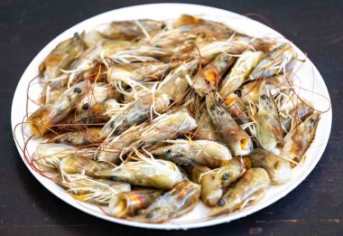 Beyaz yuvarlak tabakta taze karidesler seçici odak noktasında izole edilmiş. Karides kafa.