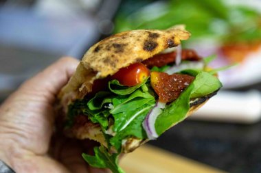 Geleneksel İtalyan Napolitan panuozzo, zanaatkar pizza hamuru, roka ve güneşte kurutulmuş domateslerle hazırlandı.