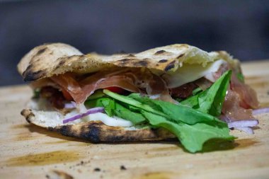 Geleneksel İtalyan Napolitan panuozzo, zanaatkar pizza hamuru, roka ve güneşte kurutulmuş domateslerle hazırlandı.