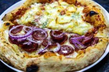 En otantik Brezilya pizzası, yarım sucuklu, soğanlı ve dört peynirli.