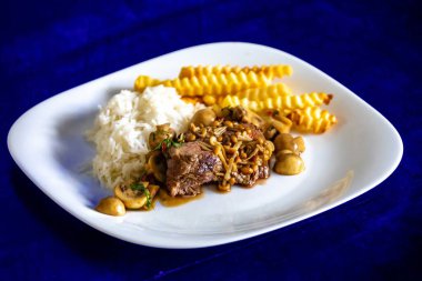 Lüks ve enfes bir yemek, mantar soslu fileminyon yanında da beyaz pirinç ve patates kızartması. Pas soslu fileminyon.