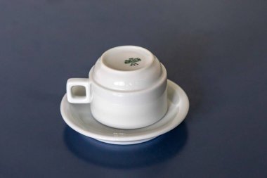 Mavi bir yüzey üzerinde beyaz seramik fincan ve çay tabağı.