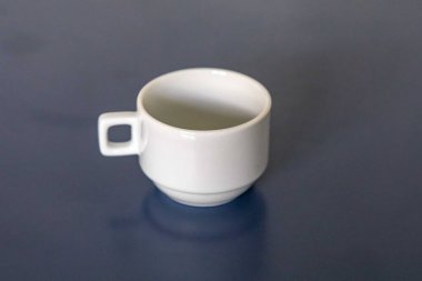 Mavi bir yüzey üzerinde beyaz seramik fincan ve çay tabağı.