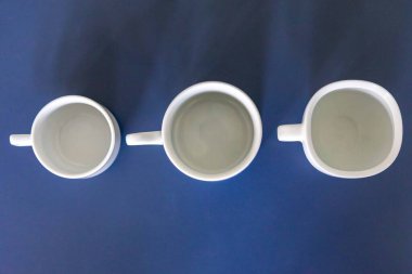 Mavi bir yüzey üzerinde beyaz seramik fincan ve çay tabağı.