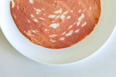 Beyaz bir tabakta dilimlenmiş bir sucuğun yakın çekimi.