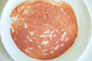 Beyaz bir tabakta dilimlenmiş bir sucuğun yakın çekimi.