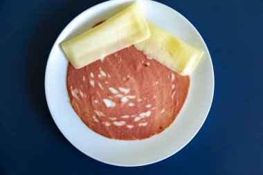 Beyaz bir tabakta dilimlenmiş bir sucuğun yakın çekimi.