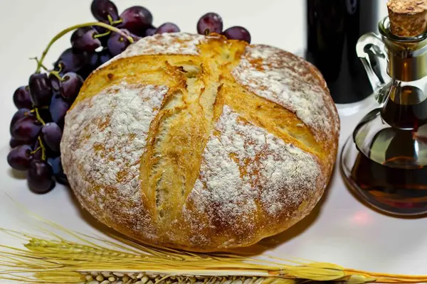 Köy ekmeği, zeytinyağı, şarap, üzüm, tespih ve buğday kulaklı Katolik kutsal masası. İsa 'nın bedeni ve kanı