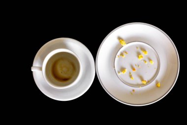 Boş kahve bardağını mısır unu kırıntılarıyla dolu boş tabağın yanına koy. Kopya alanı ile siyah arkaplanda izole