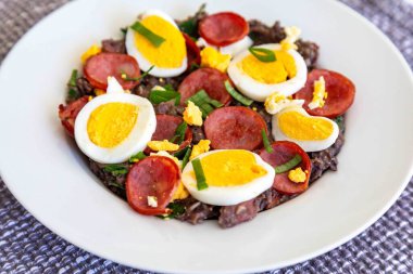 Geleneksel siyah fasulye eteği, lahana, sosis, pastırma ve yumurta. Minas Gerais 'den klasik bir köy yemeği.