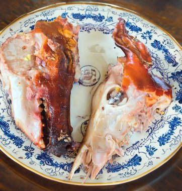 Kızarmış domuz kafası beyaz bir tabakta yarıya bölünür. Dünyanın en egzotik ve kırsal yiyeceği, pişmiş domuz kafası.