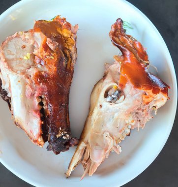 Kızarmış domuz kafası beyaz bir tabakta yarıya bölünür. Dünyanın en egzotik ve kırsal yiyeceği, pişmiş domuz kafası.