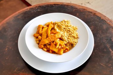 Dana işkembesi, beyaz fasulye ve tropikal baharatlarla hazırlanmış klasik bir Brezilya yemeği, kavrulmuş kaju unundan yapılan geleneksel farofa ile servis edilir..