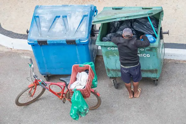 Brezilya, 8 Ağustos 2025, şortlu, şapkalı ve parmak arası terlikli, tanımlanamayan, yukarıdan görülen geri dönüşüm için çöp toplayan adam