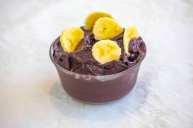 En otantik Brezilya aa 'sı, Euterpe oleracea, minimalist bir kasede muz ve uyumlu bir ortam. Süper gıda enerjisi ve vitaminler