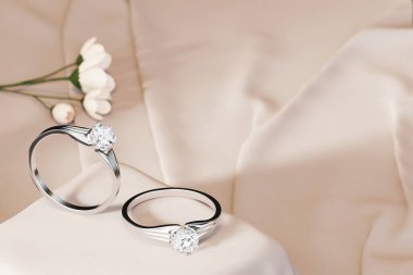 Silver Couple Diamond Rings 3D Rendering Placed on Soft Pink Cloth Soft Focus with Decoration
