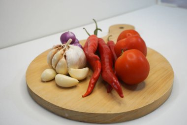 Garlic, Chili, red onion and tomatoes on a wooden coaster, High Angle shot.