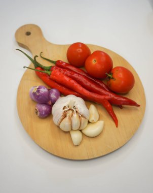 Garlic, Chili, red onion and tomatoes on a wooden coaster, High Angle shot.
