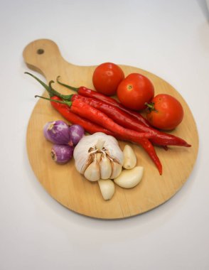 Garlic, Chili, red onion and tomatoes on a wooden coaster, High Angle shot.