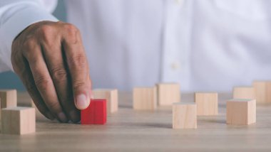 The young businessman goes to the red wooden block placed on the table ,Effective personnel management in the organization,Business solutions, success and strategy concept.