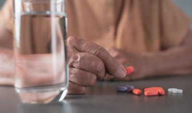 The old woman picked up a multicolored pill that was placed on the table, to treat her sickness.healthcare and medical concepts