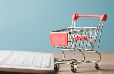 shopping cart and keyboard keys All were placed on a wooden table. Ordering products via the Internet online in the modern era is a shopaholism concept. Shopping service on The online web.