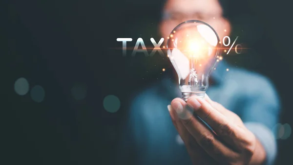 Businessman holding a light bulb ,Effective tax deduction planning ideas for individuals and companies ,Calculating business tax rates and financial budgets , Correct tax rate reduction