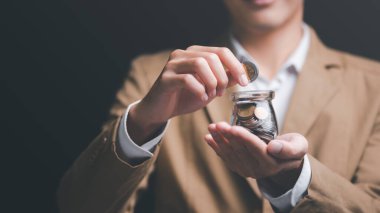 Man putting coins into a glass jar ,finance and banking, fund growth and savings concept, saving money for the future, efficient financial planning,saving for retirement,protection of your money
