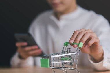 Man's hand grabbing a shopping cart,Consumer society,shopaholism concept,Shopping service on The online web and offers home delivery,Connecting merchants and customers around the world,online payment