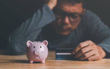 Piggy bank, credit card and man with uneasiness,unsolvable financial problem concept,unemployment, poverty, unpaid debts,business loss, bankruptcy and crisis,Anxious about future financial crises