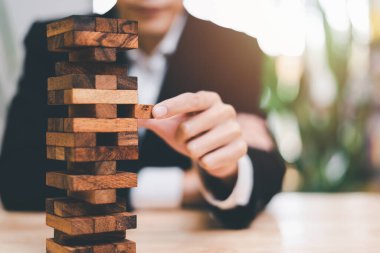 Businessman pulling a jenga wooden box,financial risk management and strategic planning,through data analysis for continuous improvement,Visionary Decisions for Leadership Success 