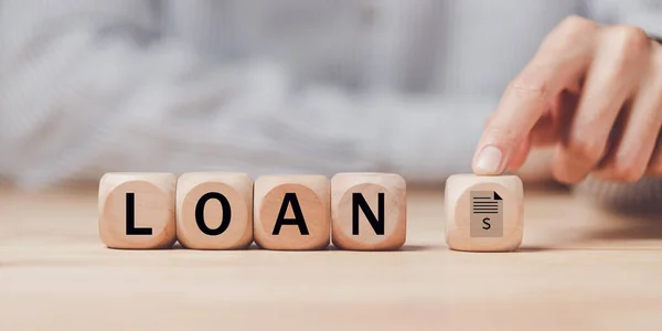 Tahta bir bloğu işaret eden adam, bankacılık kredisi onayı, ipotek kredisi onayı veya gayrimenkul alımı, mali kredi başvurusu, mali kredi anlaşması, ipotek başvurusu