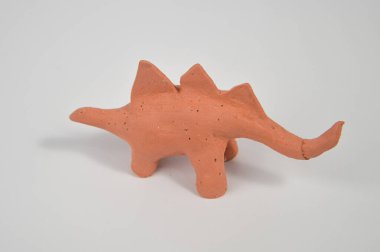 Stegosaurus 'un bitmemiş çocuk zanaatı, kilden yapılmış ve beyaz bir zemin üzerinde.