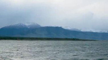 Patagonya, Şili 'de hareket eden göl suları ile birlikte yüksek dağ manzarası üzerinde fırtına ve bulutların gün batımı zamanı. Yüksek kalite 4K görüntü